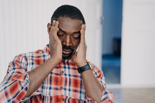 man with migraine holding sides of head