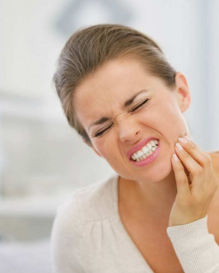 picture of a woman holding her jaw because of toothache